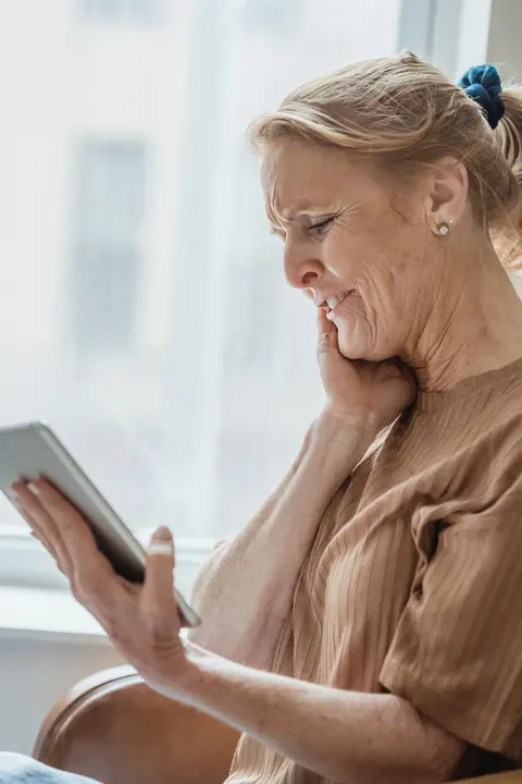 An older woman smiling while choosing an ad-free game on a tablet