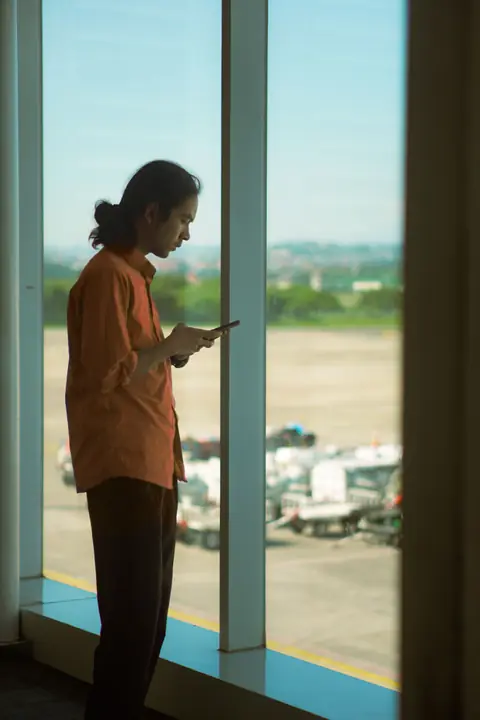 Business traveller checking airplane mode games on a phone at an airport