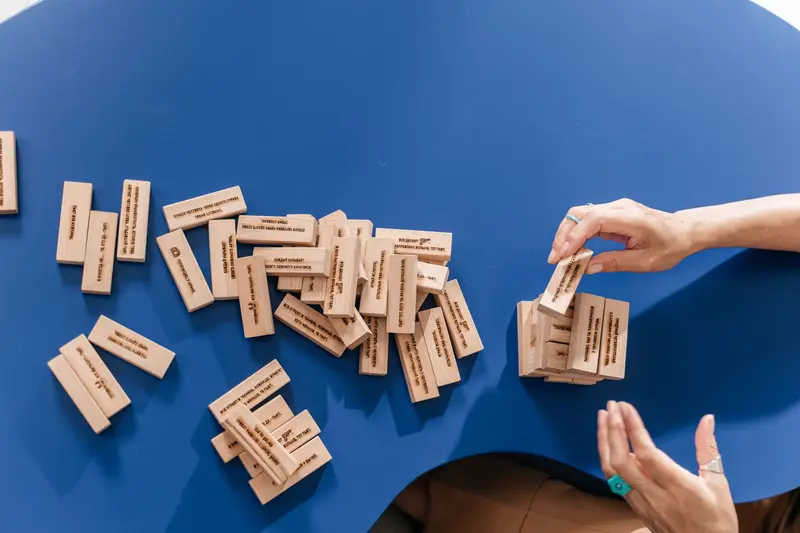 Hands stacking wooden blocks to illustrate base-building strategy and balance