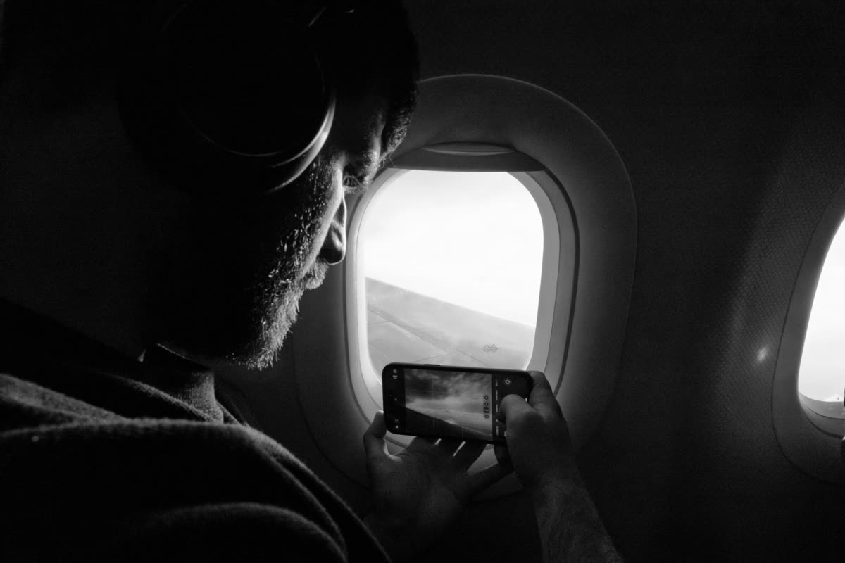 A traveller using a smartphone beside an airplane window