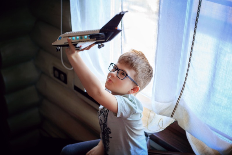 Child preparing for a flight with an airplane toy