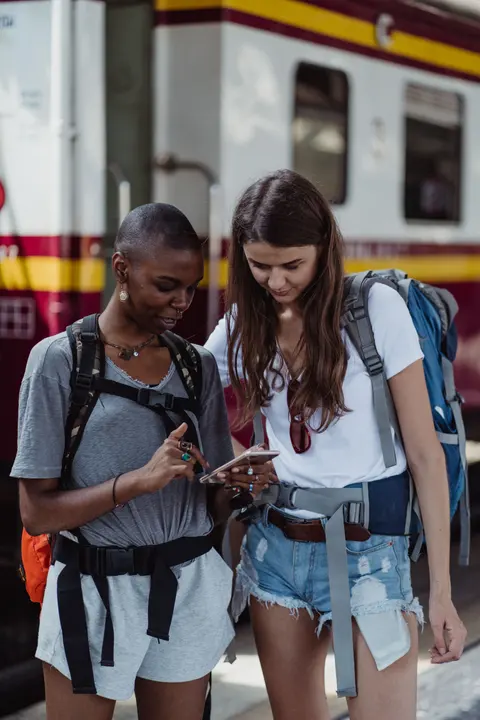 Two travellers sharing one phone to play fun pass-and-play games offline