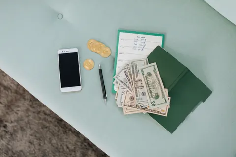 A smartphone, coins, cash, and a notebook representing a social casino business model