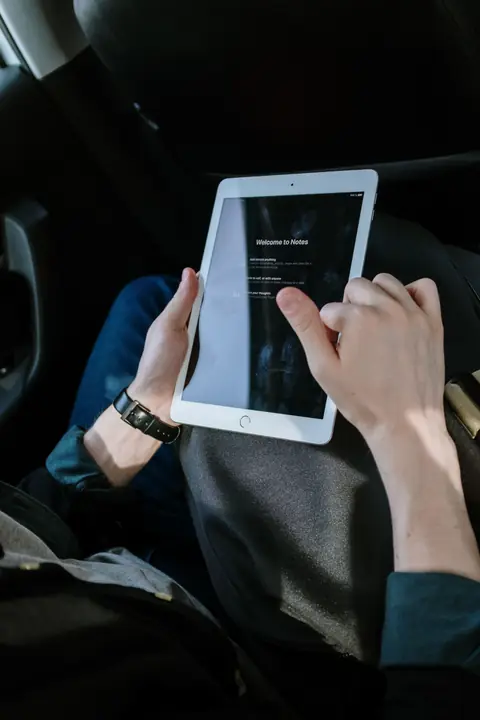 Passenger holding a white iPad while travelling in a car
