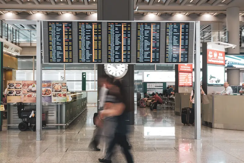 Travellers beneath departure boards after preparing offline games for a wait