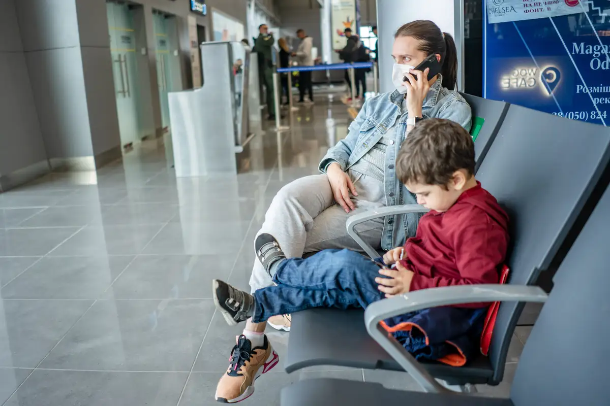 A parent and child using mobile devices while waiting for a flight