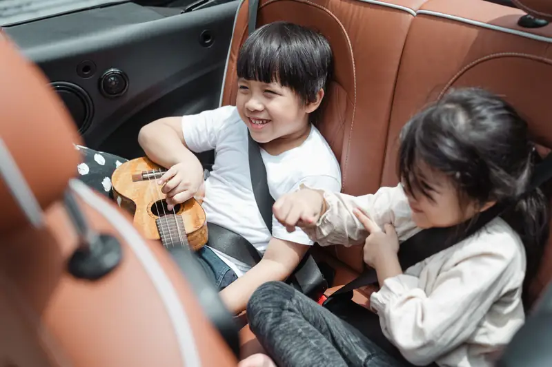 Two buckled-in children playing together during a road trip
