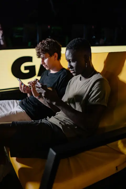 Two friends focused on games on their phones while sitting together