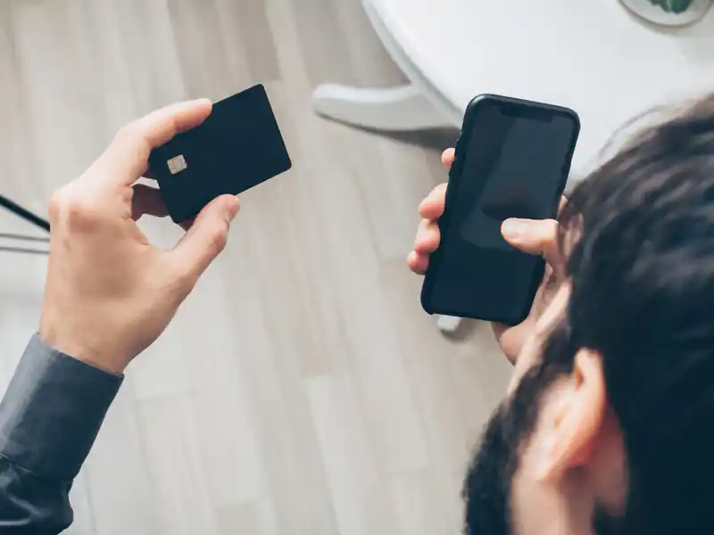 Person holding a smartphone and credit card to illustrate buying power in a mobile game