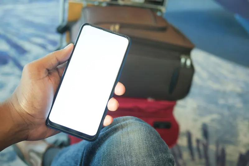 A phone and luggage at an airport, ready for travel