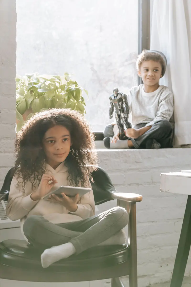 Two children spending calm time with a tablet and toy at home